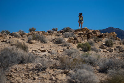 Low angle view of woman on rock against clear sky