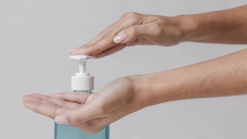 Close-up of hands holding glass over white background