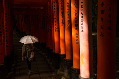 Woman with umbrella walking at temple