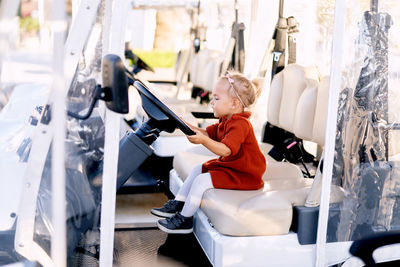 Side view of boy sitting on display at store