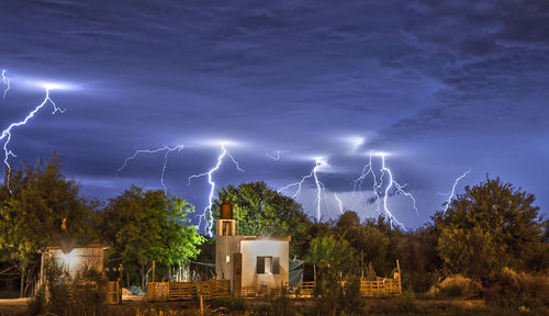 Lightning over illuminated buildings against sky at night