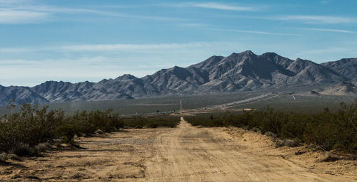 Empty dirt road leading towards mountains