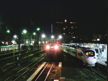 Train on illuminated railroad tracks against sky at night