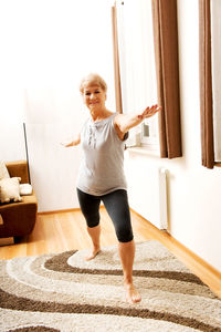 Portrait of senior woman practicing warrior pose at home
