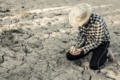 Woman kneeling on barren field