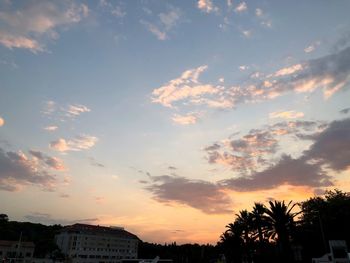 Low angle view of silhouette trees and buildings against sky during sunset