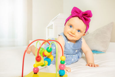 Portrait of cute baby girl sitting on bed at home