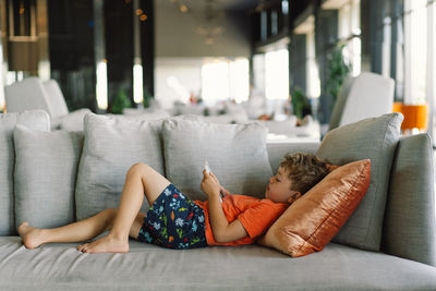 Low section of woman relaxing on bed at home