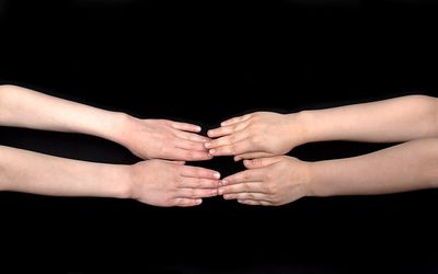 Midsection of couple hands against black background