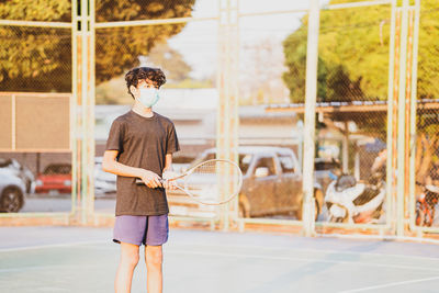 Boy holding racket while standing in court