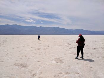 Rear view of man standing on beach against mountain