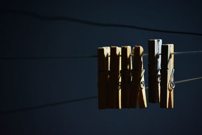 Close-up of clothespins hanging on rope against wall