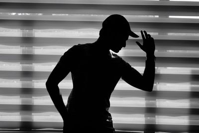 Silhouette man standing against window