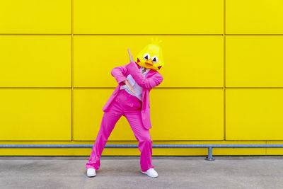 Full length of a girl standing on yellow wall