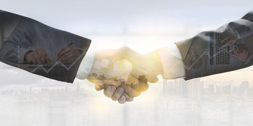 Multiple exposure of business partners shaking hands and cityscape