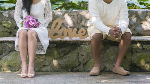 Low section of friends sitting on retaining wall