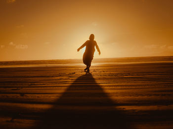 Full length of silhouette woman standing at beach during sunset