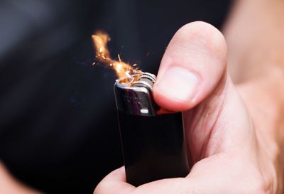 Midsection of person igniting cigarette lighter