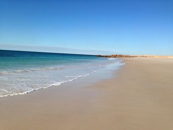 Scenic view of beach against clear blue sky