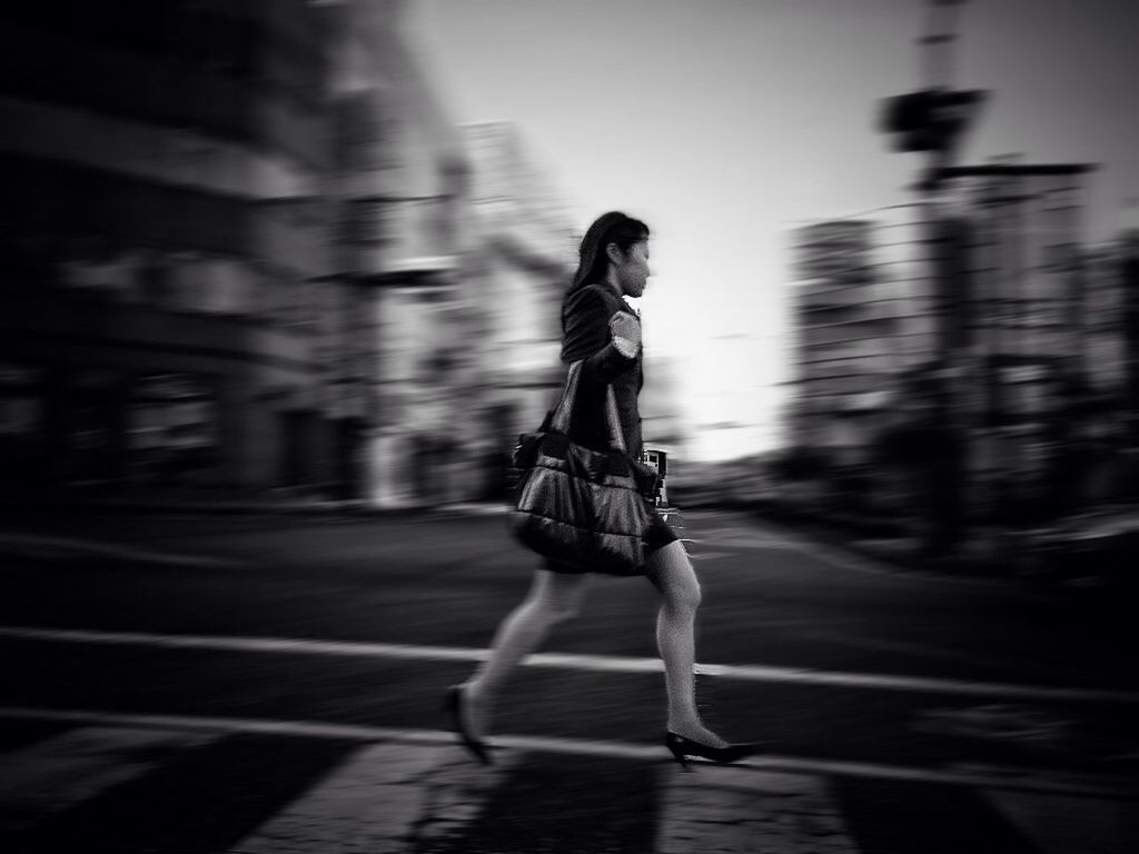 full length, street, lifestyles, casual clothing, walking, road, rear view, leisure activity, transportation, motion, on the move, city life, standing, blurred motion, person, focus on foreground, holding, front view