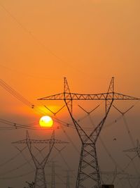 Low angle view of silhouette electricity pylon against sky during sunset