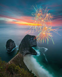 Firework display over sea against sky