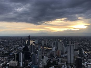 Aerial view of city against cloudy sky during sunset