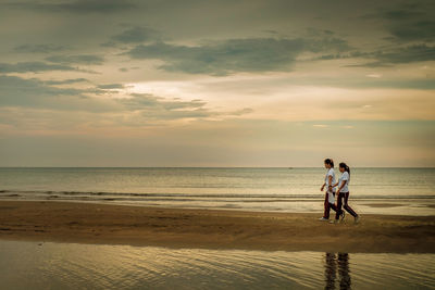 People at beach against sky