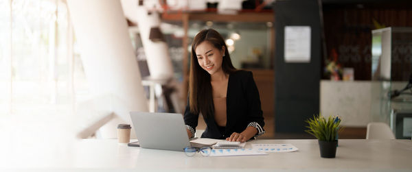 Young woman using mobile phone while sitting on table