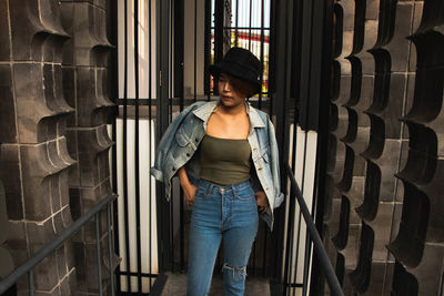 Young woman looking away standing against metal entrance