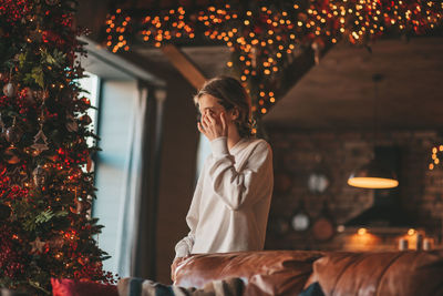 Portrait of candid authentic smiling boy teenager having fun emotion at wooden lodge xmas decorated