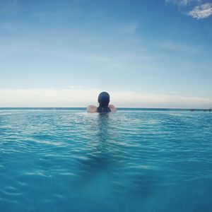 Young woman in swimming pool in sea against sky