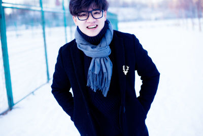 Portrait of smiling young man standing on snow