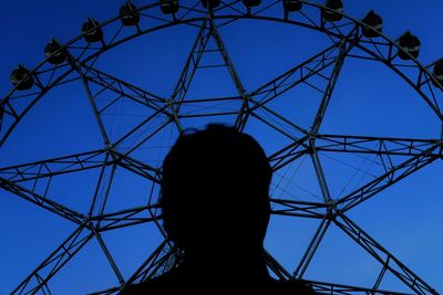 Low angle view of silhouette man against clear blue sky