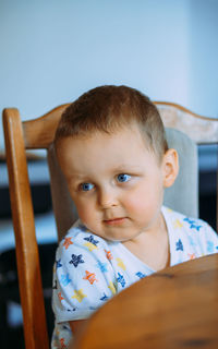 Portrait of cute baby boy sitting on sofa at home