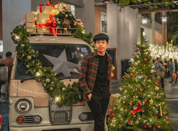 Portrait of young man standing by christmas tree