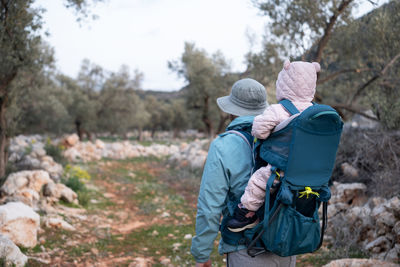 Rear view of father with baby hiking on trail