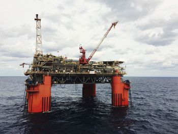 Oil drilling platform on sea against cloudy sky