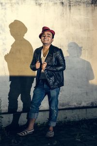 Portrait of young man standing against wall