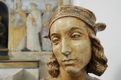 Bust of raffaello sanzio, known as raphael. on background there is a fresco painted by raffaello.