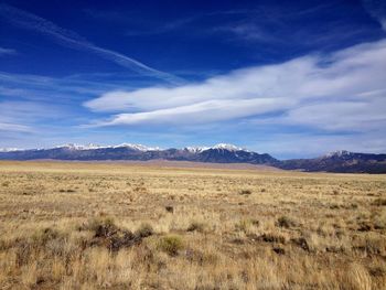 Scenic view of field and mountains against blue sky