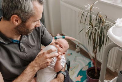 Father feeding baby with bottle of baby formula