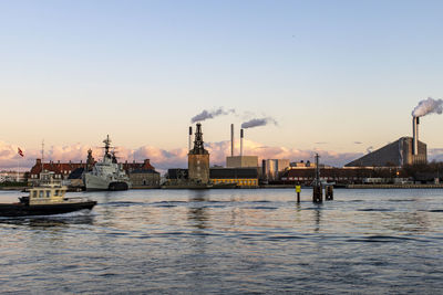 Commercial dock by sea against clear sky during sunset