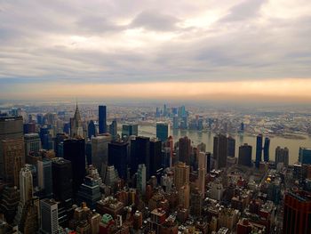 Aerial view of buildings in city against cloudy sky