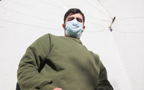 Low angle portrait of man wearing face mask outdoors