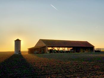 Houses on field against sky during sunset