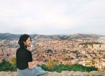 Woman looking at cityscape against sky