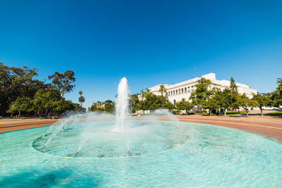 Water fountain in swimming pool against blue sky