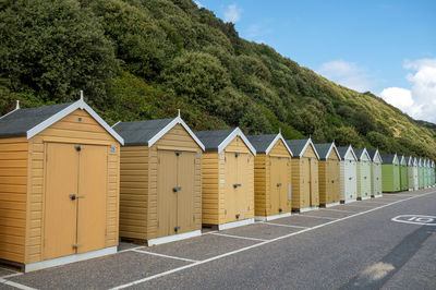Beach huts on road by sea against sky
