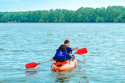 Rear view of man rowing boat in water